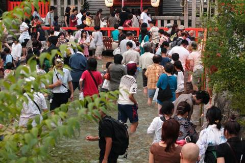 Visitors wade through the cool spring water in the heat of summer