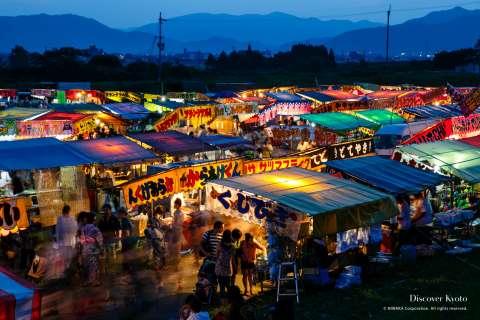 Food stalls glow at the Kameoka Heiwasai Hozugawa Fireworks Festival.