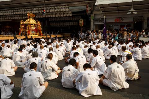 Men sit and wait before the omikoshi portable shrine during the Mikoshi Procession of Gion Matsuri.